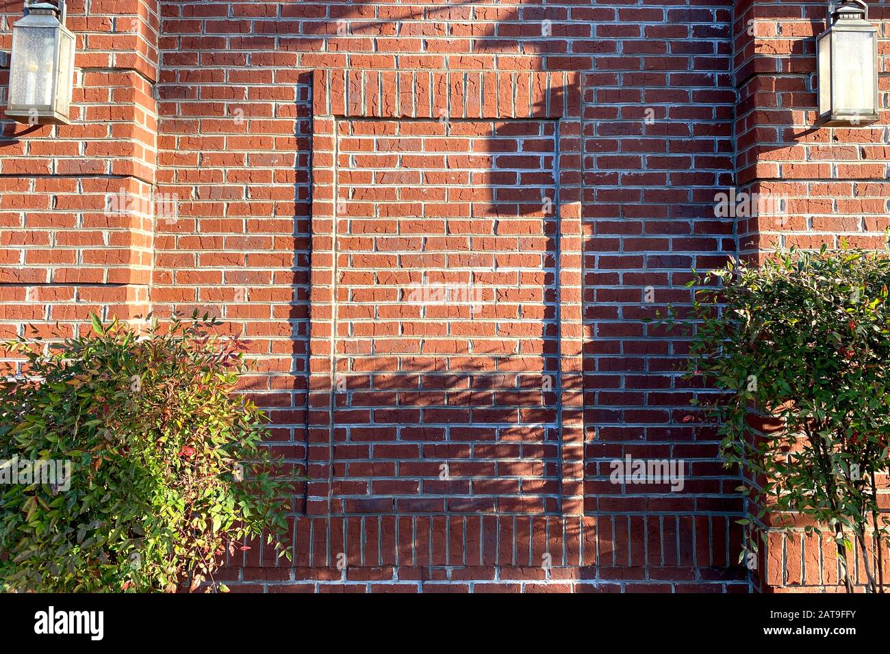 une façade en brique rouge avec des ombres profondes l'après-midi Banque D'Images