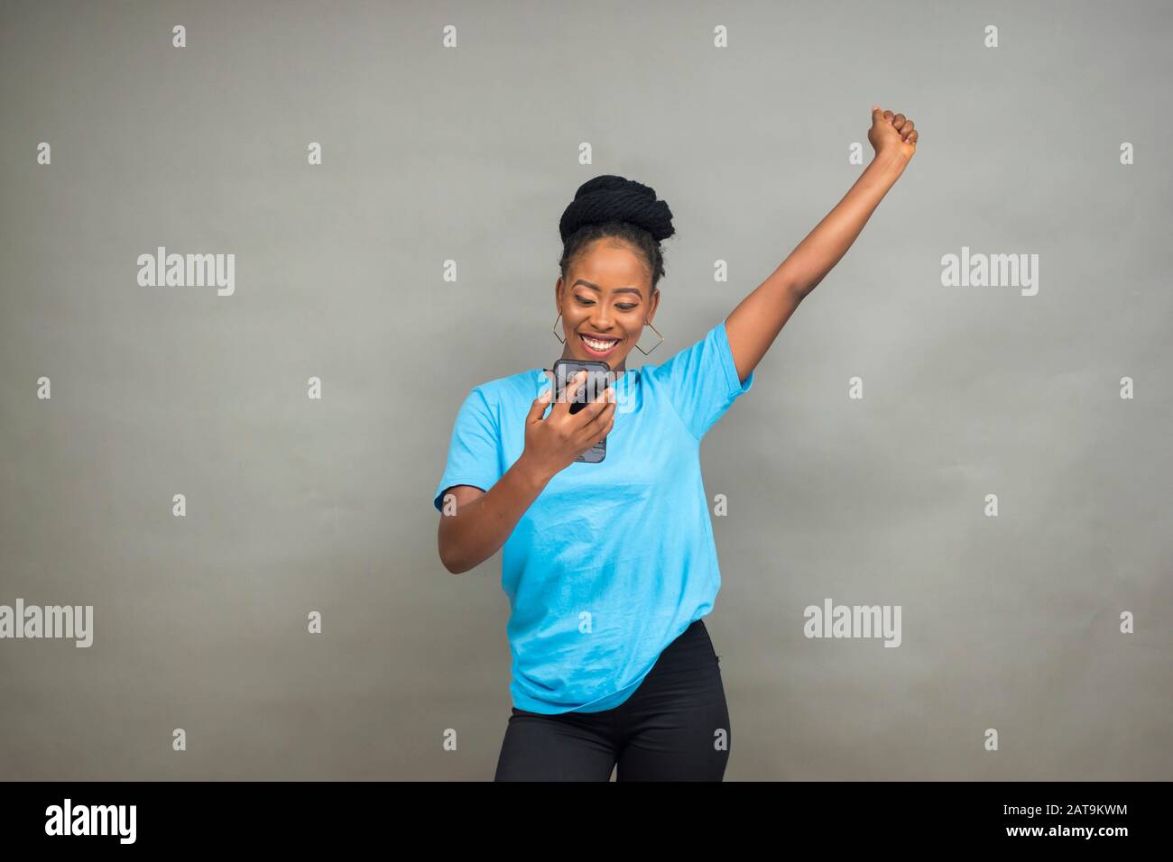 belle jeune femme noire utilisant son téléphone mobile souriant et se sentant excité Banque D'Images