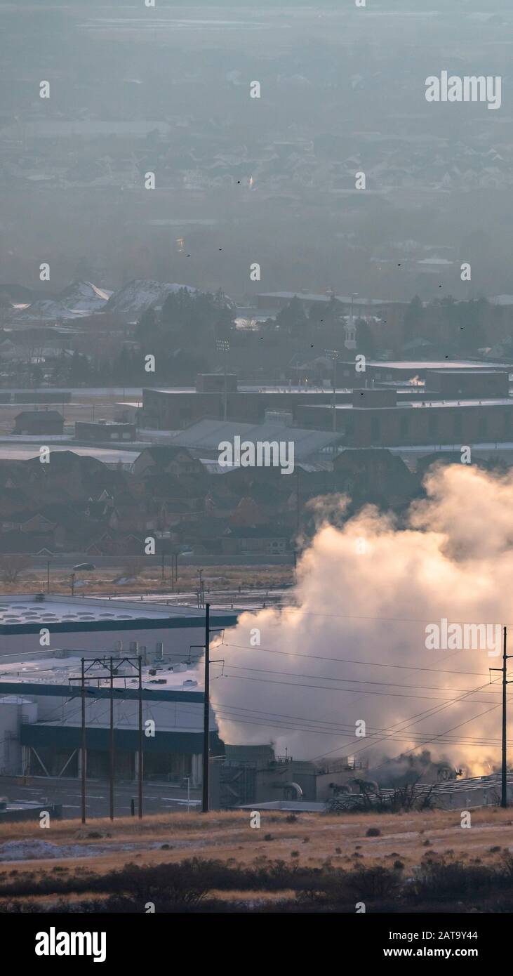 Cadre vertical usine industrielle émettant une fumée épaisse contre le paysage brumeux en hiver Banque D'Images