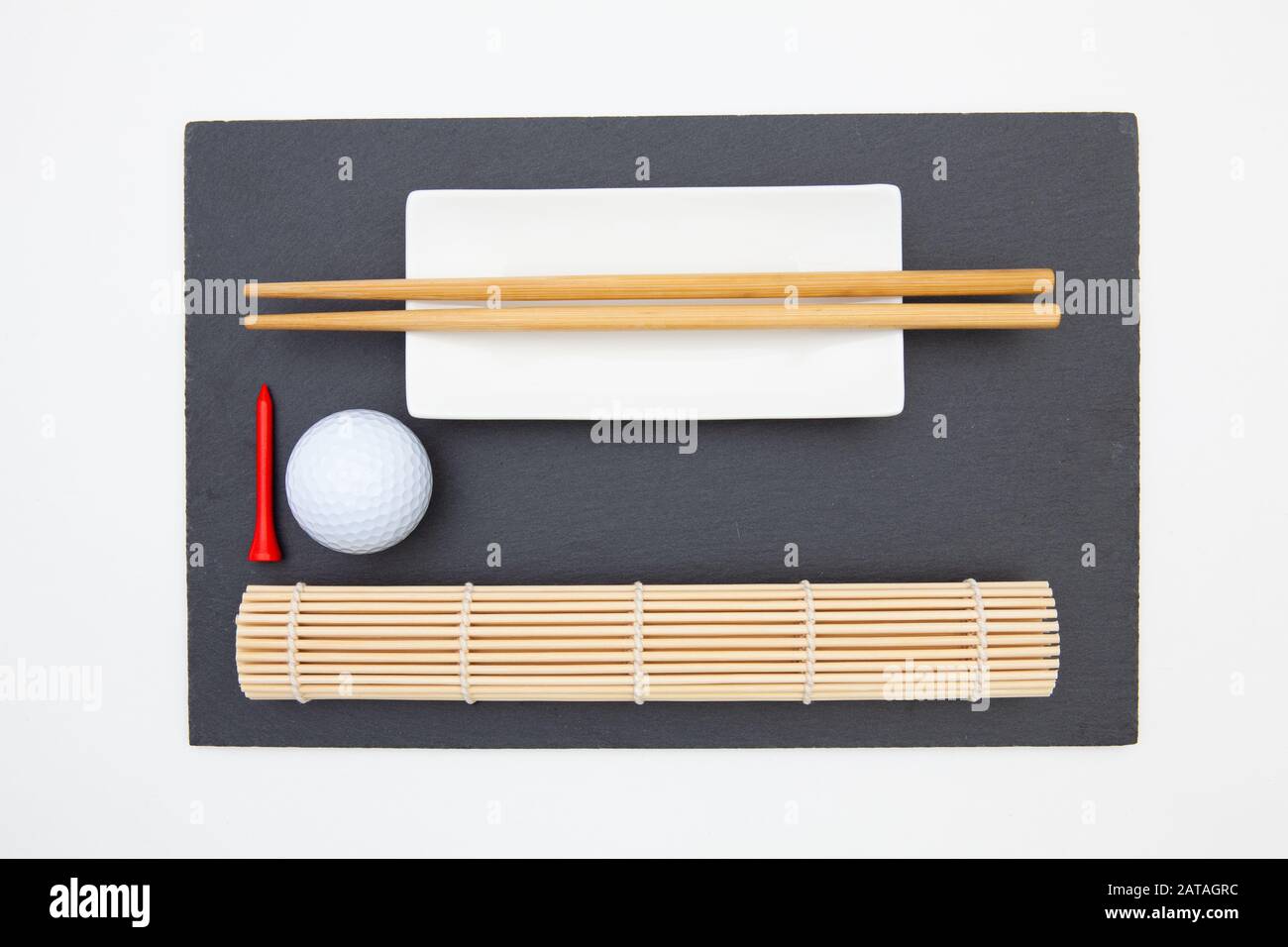 Plaque rectangulaire en ardoise avec baguettes pour sushi et ballon de golf. Design De Golf Banque D'Images