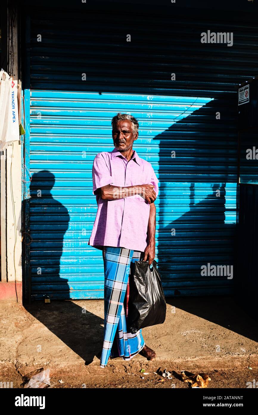 Un gars local en robe bleue debout sur le côté de la route au Sri Lanka. Banque D'Images