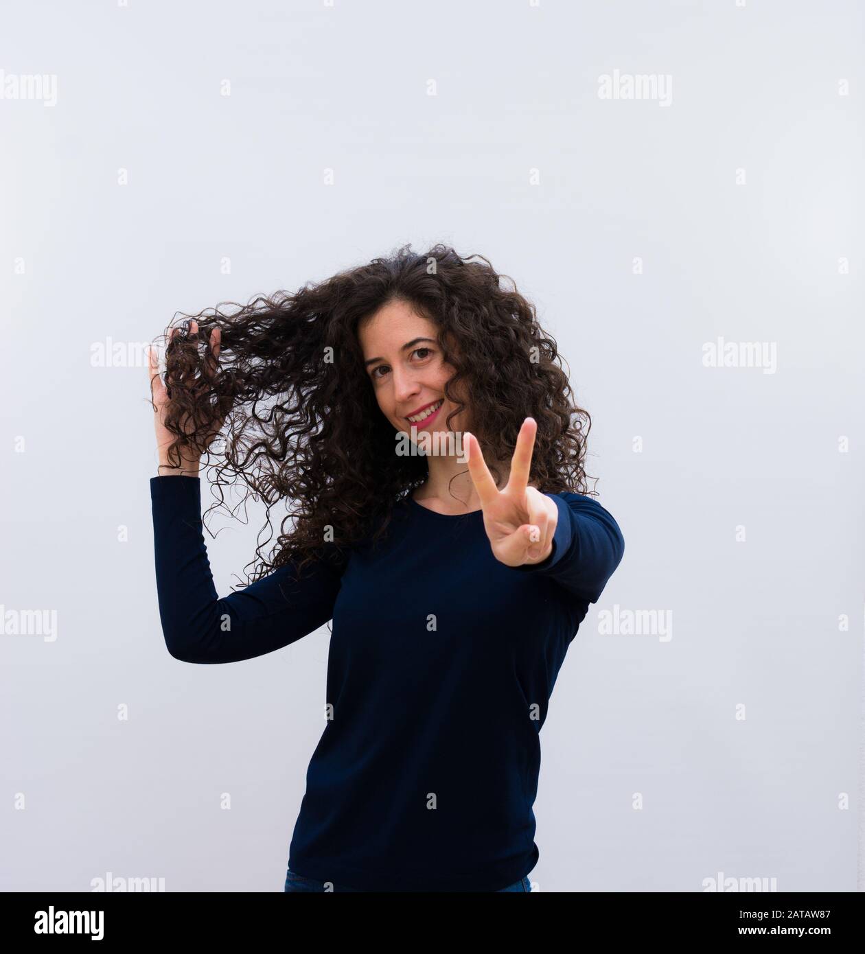 Jeune jolie femme avec des cheveux noirs et frisés montrant ses cheveux frisés Banque D'Images