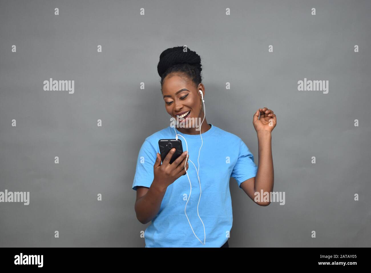 jolie jeune femme noire qui écoute de la musique et qui utilise son téléphone portable pour discuter, envoyer des sms, naviguer Banque D'Images