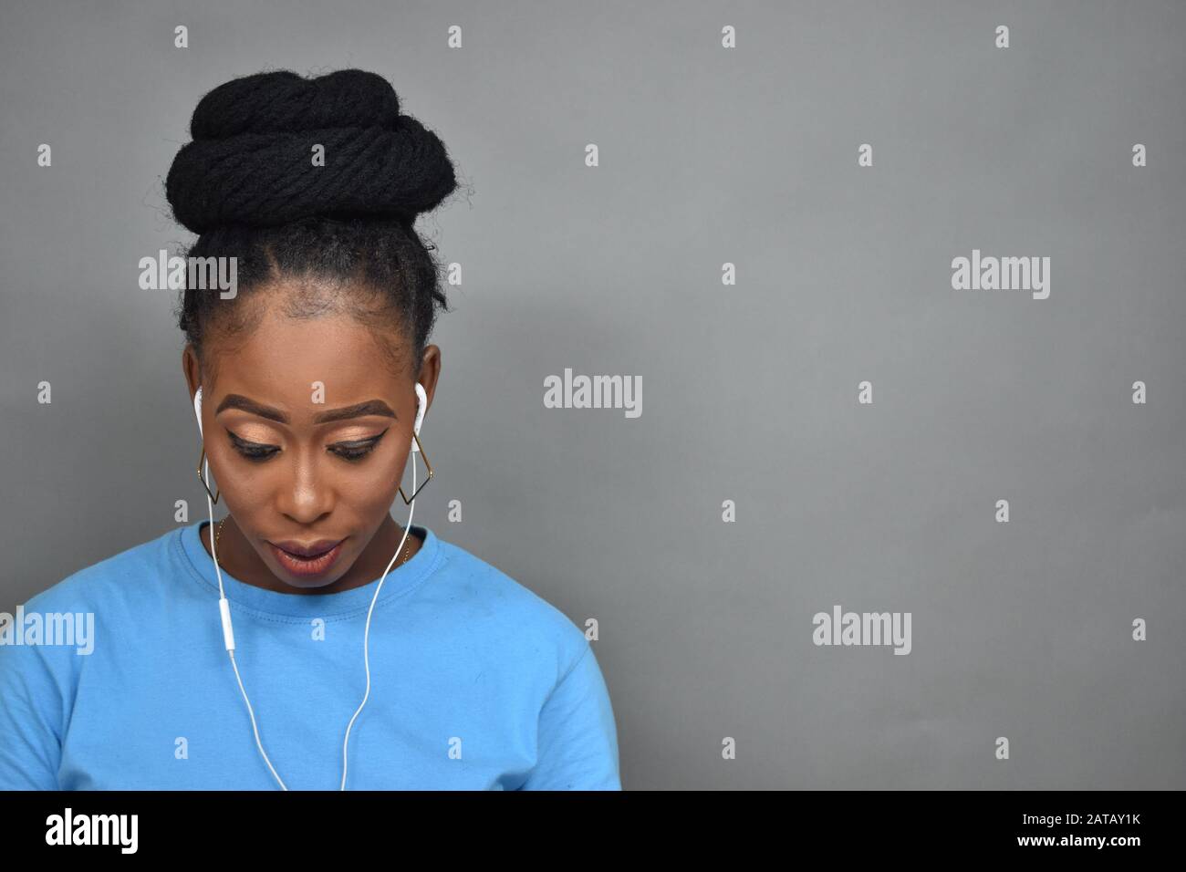 jeune femme noire avec coiffure africaine à l'écoute de la musique, à l'aide d'écouteurs Banque D'Images