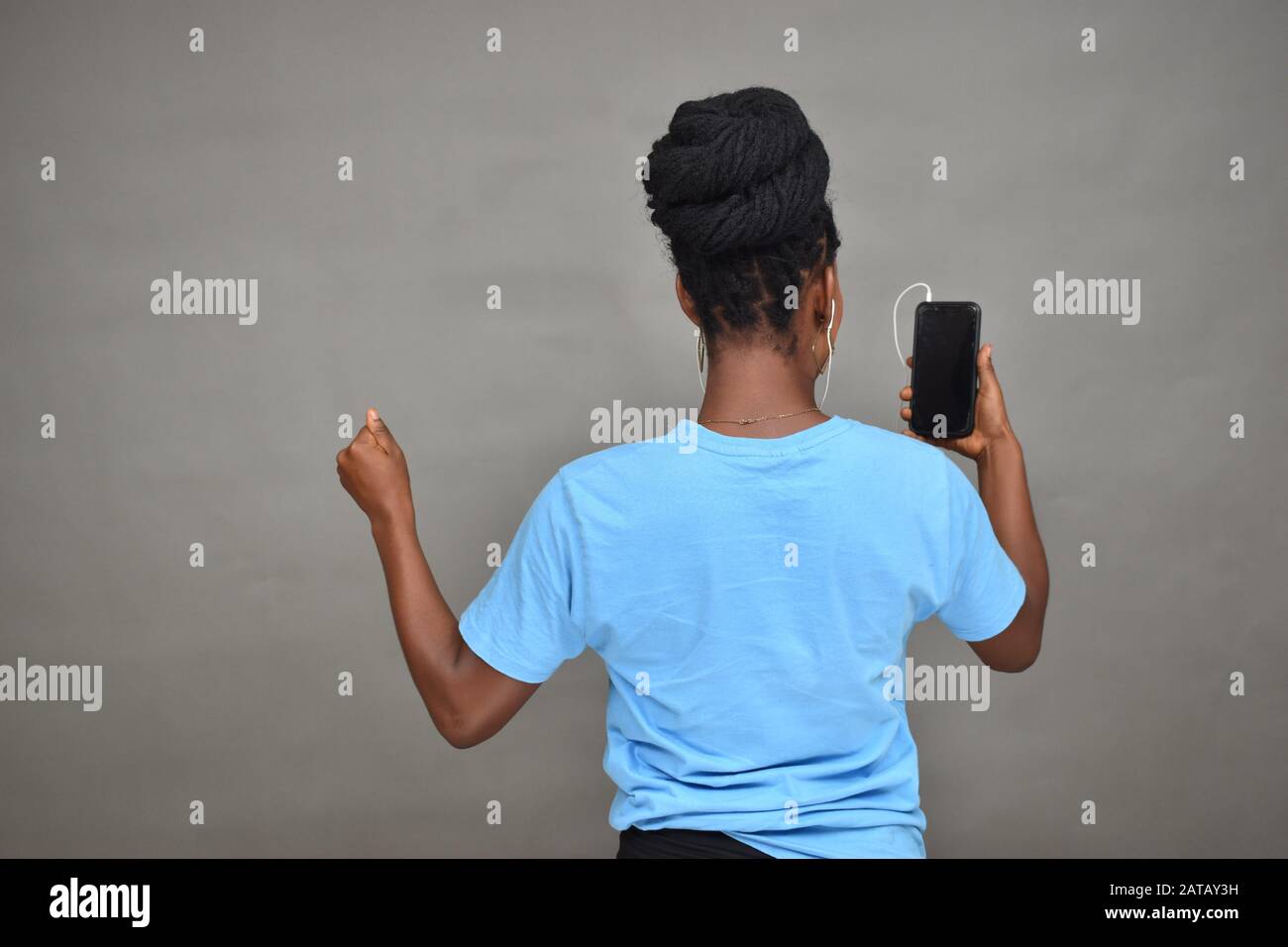 belle jeune femme noire à écouter de la musique et à regarder du contenu sur son téléphone mobile se sentant excitée Banque D'Images
