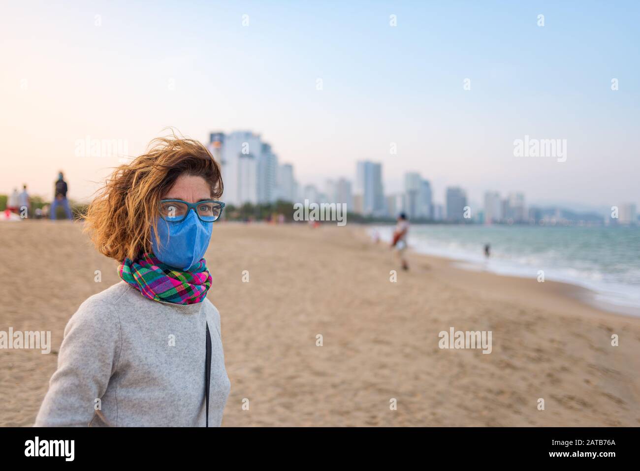 Femme caucasienne portant un masque sanitaire à l'extérieur de la plage de Nha Trang, célèbre décollement de voyage au Vietnam. Tourisme avec protection de masque médical contre r Banque D'Images