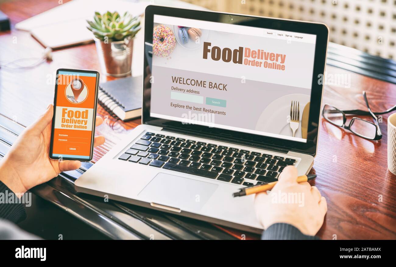 Application de commande et de livraison de nourriture en ligne sur les écrans d'ordinateur portable et de téléphone, homme au travail, bureau d'affaires. Service de livraison des commandes de plats à emporter Banque D'Images