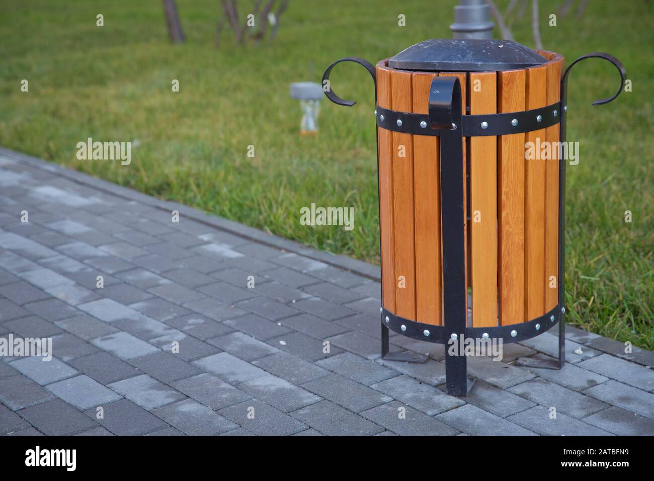 espace de copie sur la gauche. Boîte à ordures dans le parc . Une urne en bois et un confortable banc de parc vide . Poubelle jaune à l'intérieur d'une enceinte en bois à un Banque D'Images