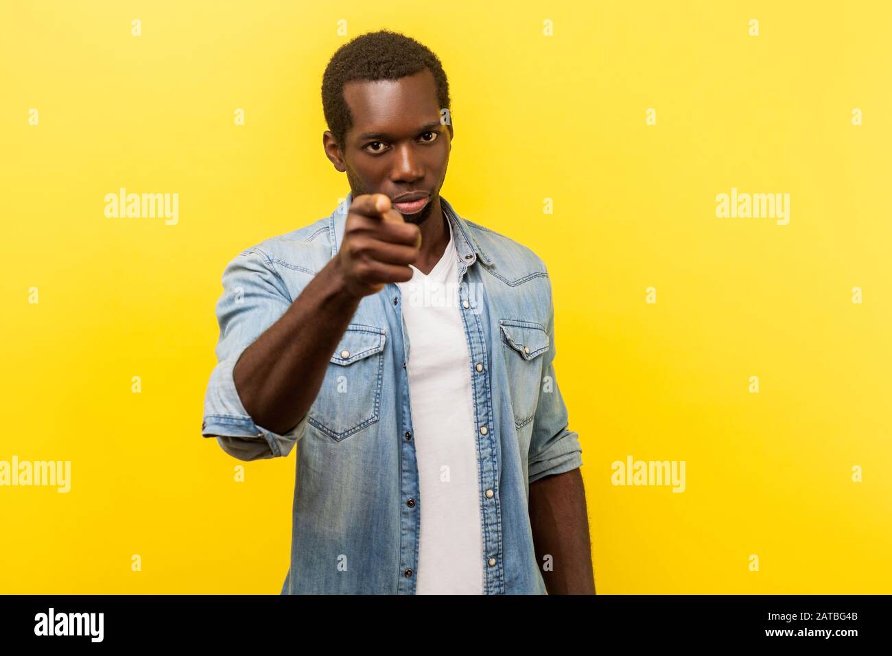 Hé toi ! Portrait d'un homme sérieux dans une chemise en denim avec manches enroulées pointant vers l'appareil photo, avertissement ou accusant d'expression bossy insatisfaite. IND Banque D'Images