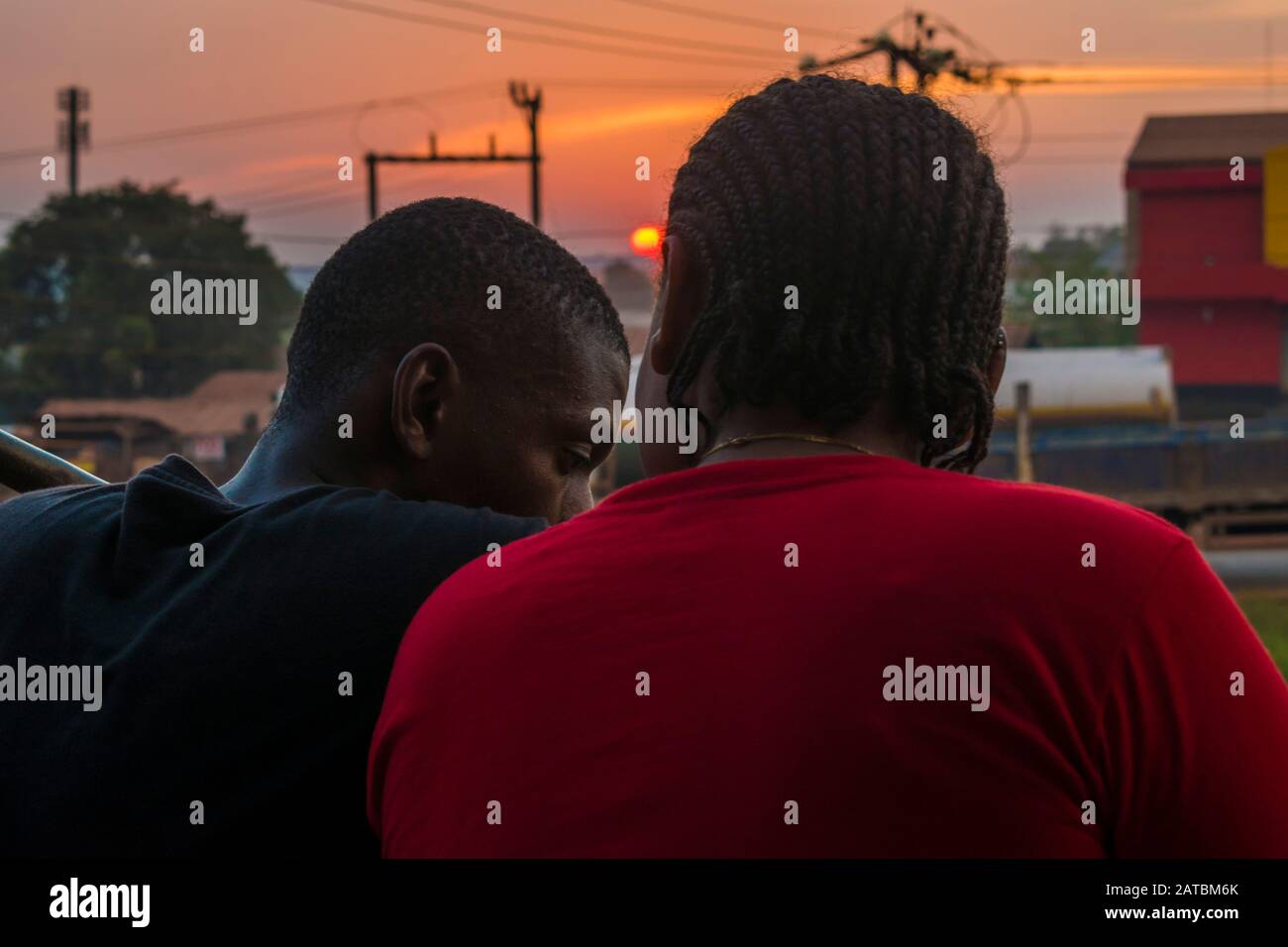 jeune homme noir et dame assis ensemble en dehors d'avoir une conversation pendant que le soleil se couche Banque D'Images