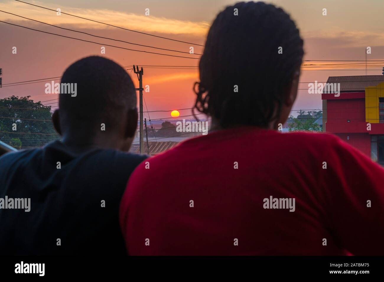 jeune homme noir et dame assis ensemble à l'extérieur pour avoir une conversation et regarder le coucher du soleil du soir Banque D'Images