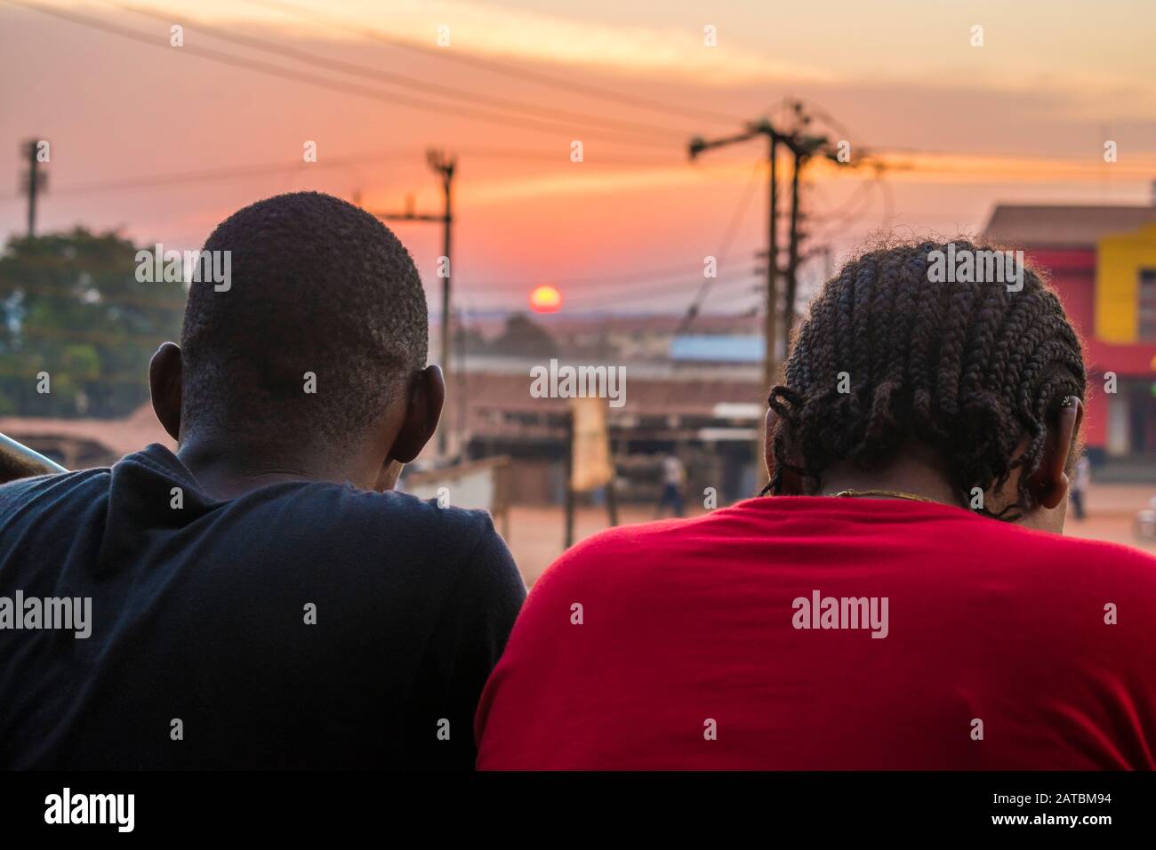 jeune homme noir et dame assis ensemble à l'extérieur pour avoir une conversation et regarder le coucher du soleil du soir Banque D'Images