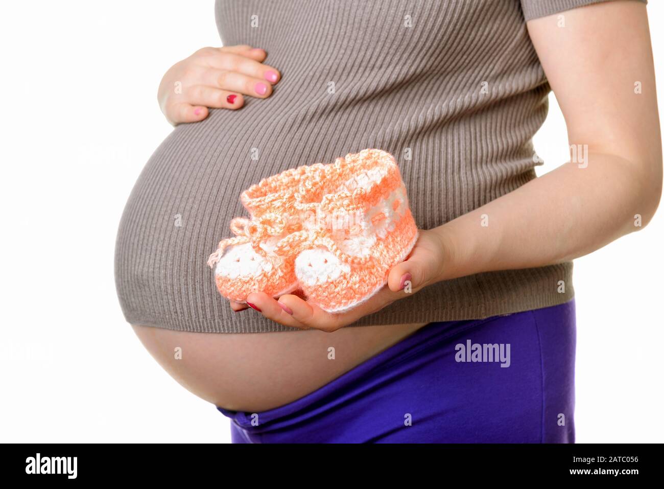 Femme enceinte tenant une belle chaussures de bébé en laine isolée sur blanc Banque D'Images Femme enceinte tenant une belle chaussures de bébé en laine isolée sur blanc Banque D'Images