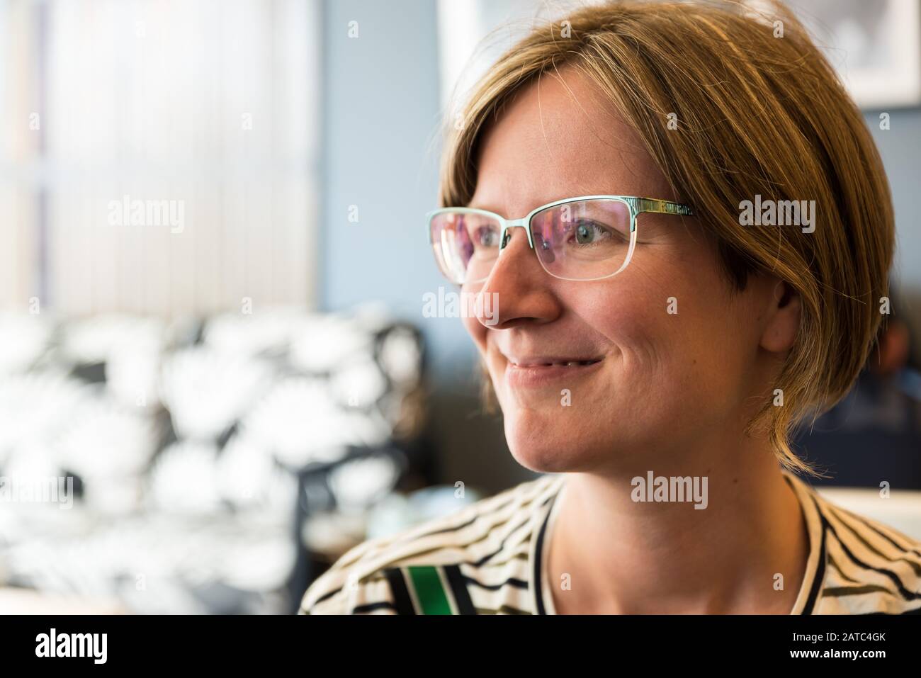 Gros plan portrait d'une femme de trente ans séduisante avec des lunettes et une chemise classique à rayures vertes Banque D'Images