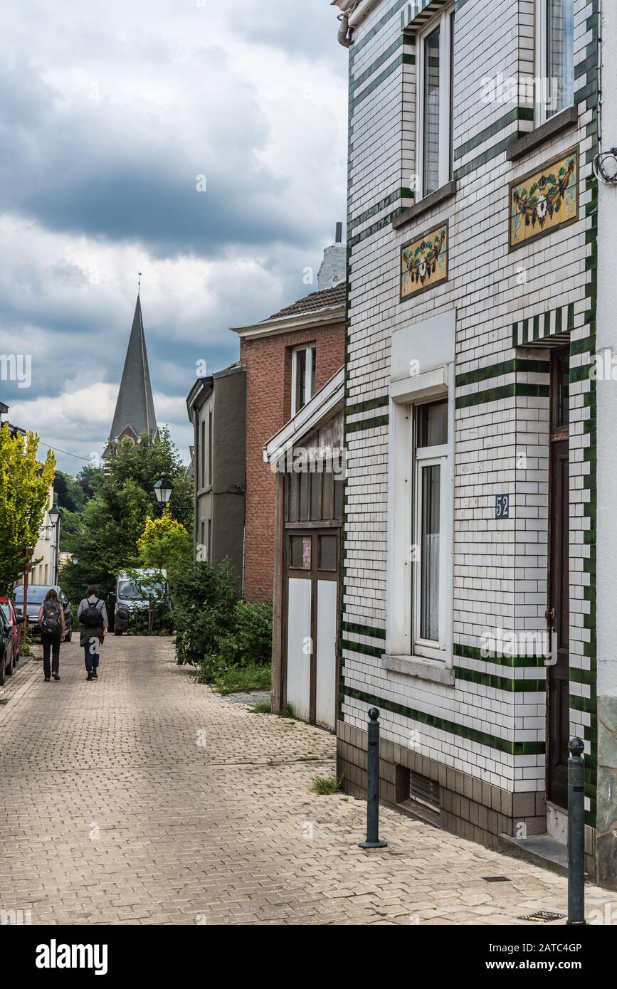 Uccle, Bruxelles / Belgique - 06 14 2019: La rue curling Saint Job avec vue sur la tour de l'église et un homme de vélo en voiture Banque D'Images