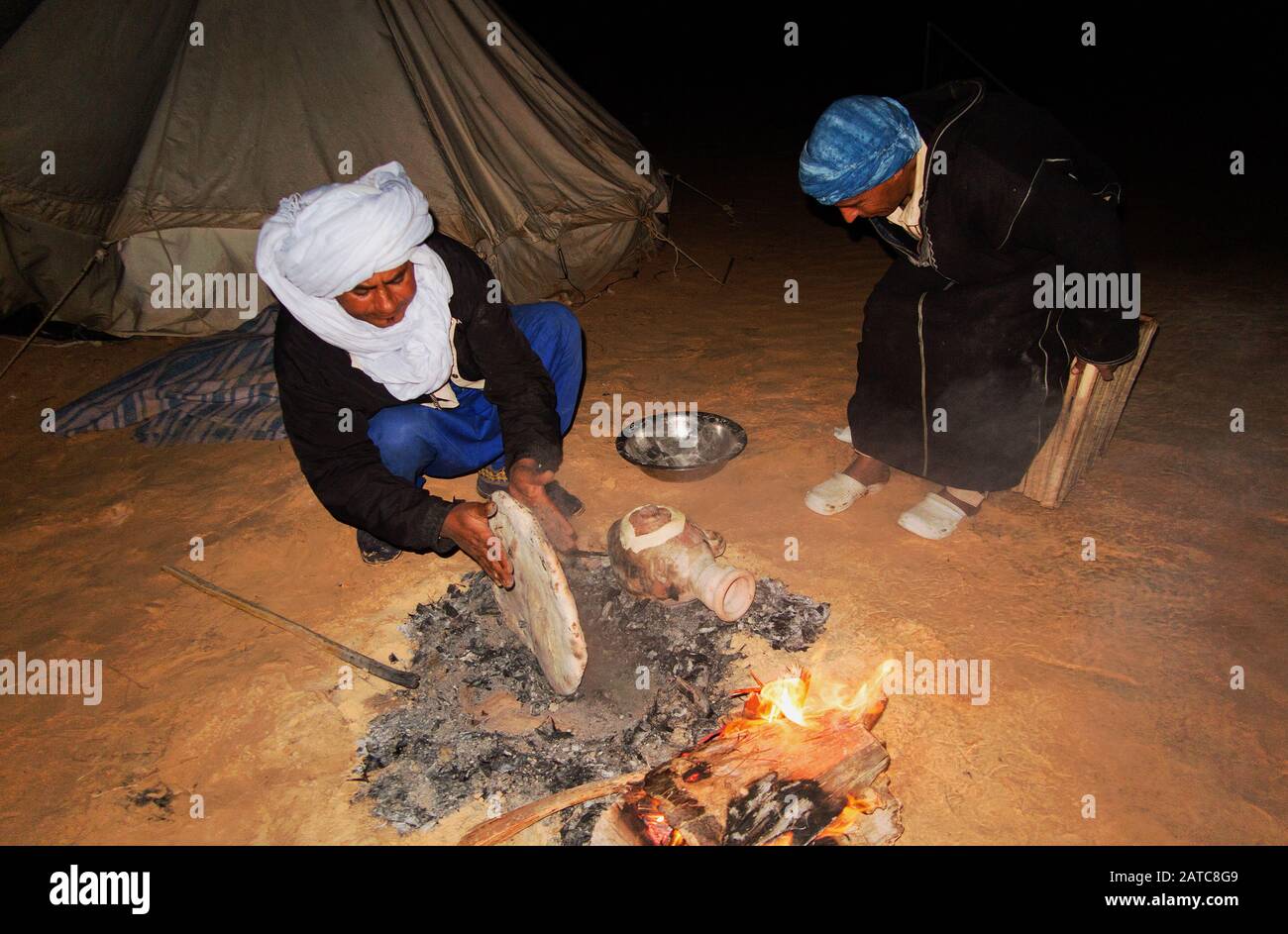 Un homme fait du pain avec du charbon de bois et du sable comme cela a toujours été fait au Sahara. Banque D'Images
