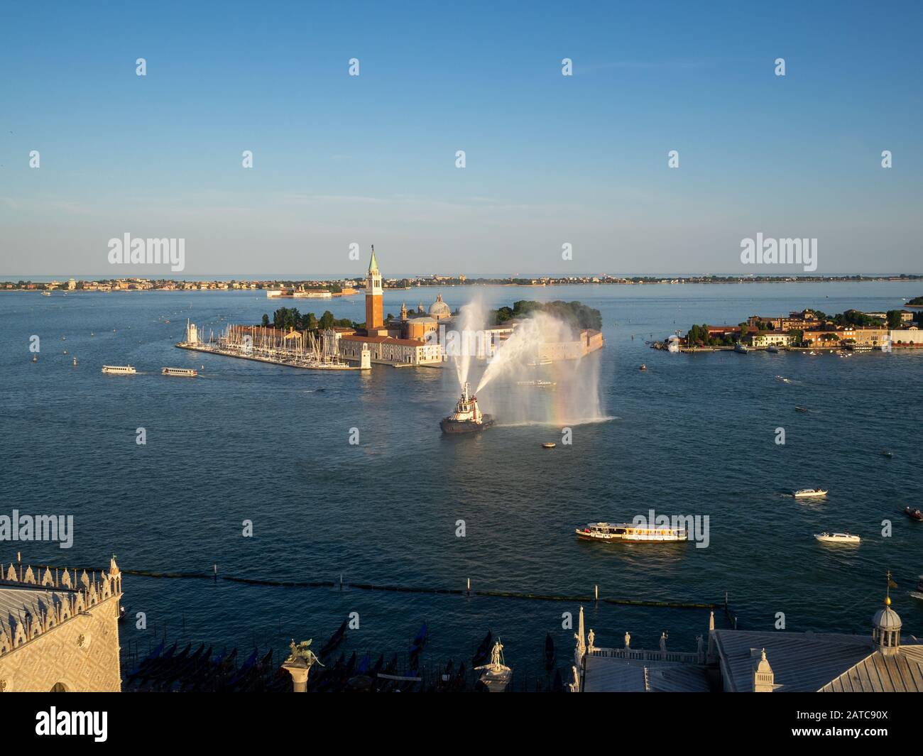 Un bateau vaporise des jets d'eau dans la lagune de Venise par l'île San Giorgio Maggiore Banque D'Images