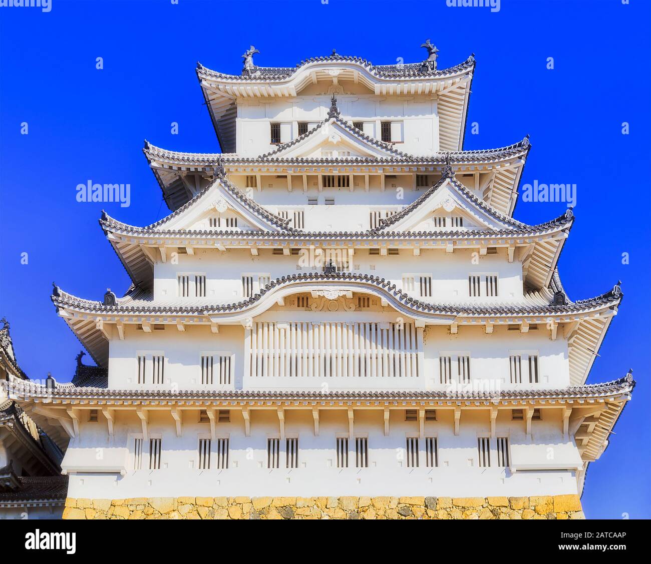 Le château blanc de Famouls dans la ville d'Himeji au Japon contre le ciel bleu clair dans la ligth de soleil de ver sur sa façade. Banque D'Images