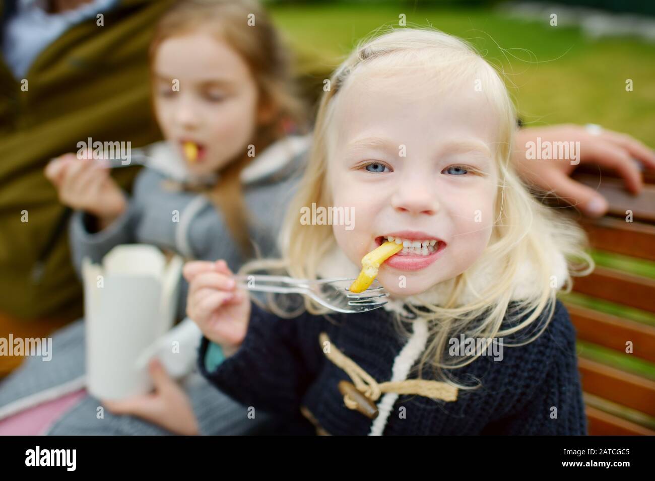Mignons petites filles mangeant des frites lors de belles journées à l'extérieur. En-cas pour les enfants. Manger des aliments malsains. Banque D'Images