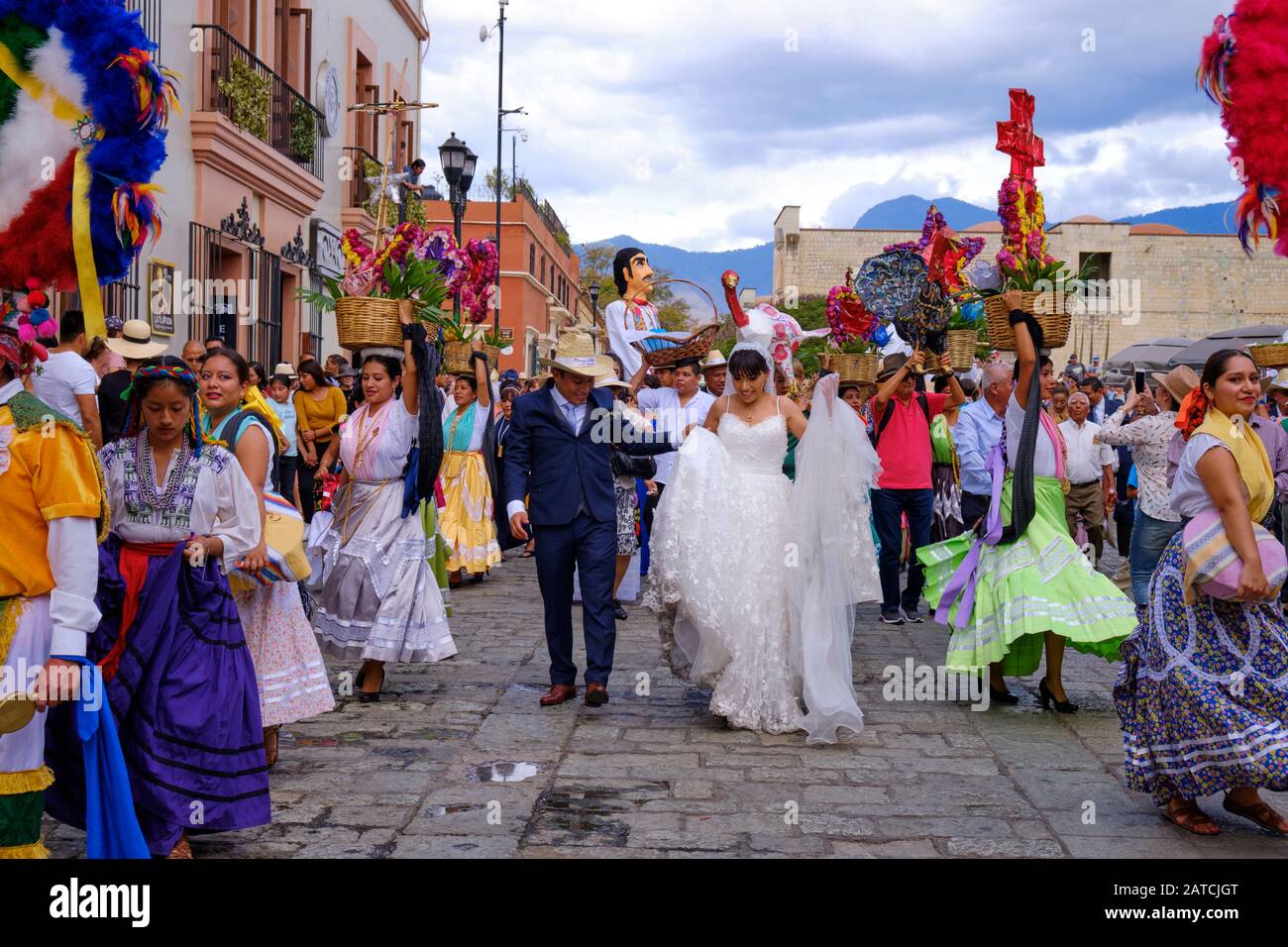 Mariée et marié encadrés par une femme dans la tenue traditionnelle partie de la parade de mariage traditionnelle (Calenda de Bodas) dans les rues d'Oaxaca. Banque D'Images