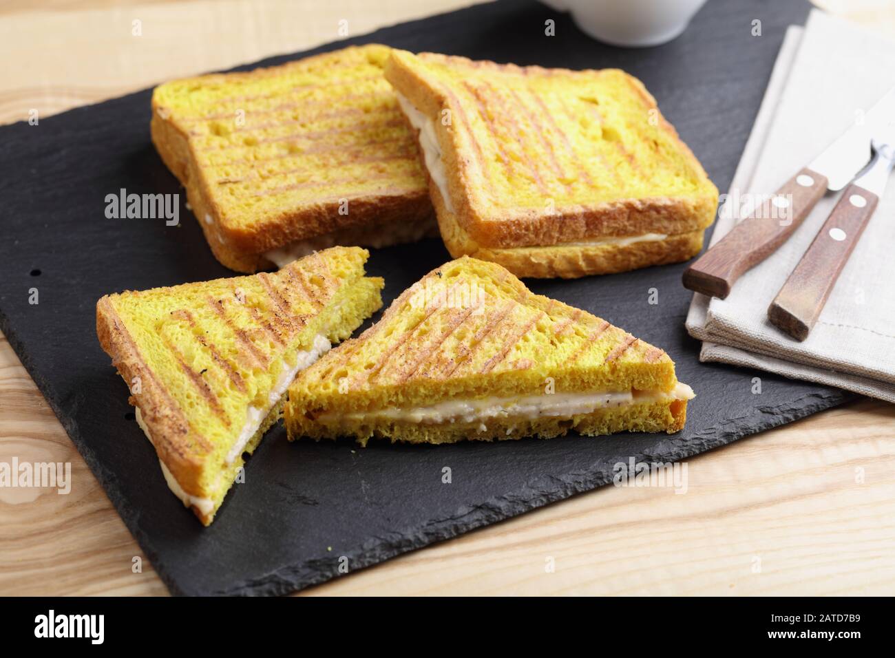 Sandwichs grillés au jambon et au fromage sur une planche à découper en ardoise. Le pain grillé avec curcuma donne une couleur jaune vif Banque D'Images