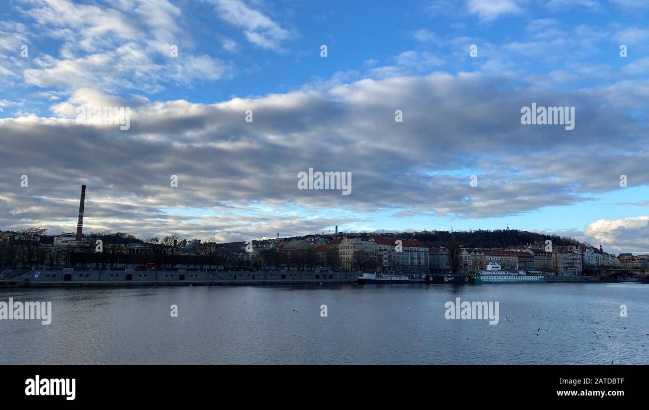 Coucher de soleil d'hiver sur la Vltava et le quartier de Smichov. Réflexions du soleil et nuages sur la surface. Prague, Bohême. Banque D'Images
