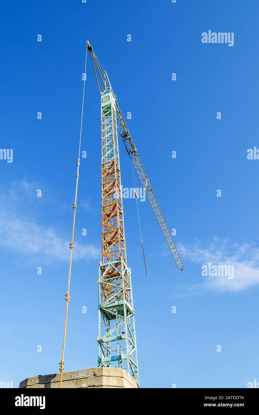Tour de construction bleu jaune grue contre le ciel bleu clair un jour ensoleillé d'hiver. Machines de construction modernes. Vue de bas angle. Banque D'Images
