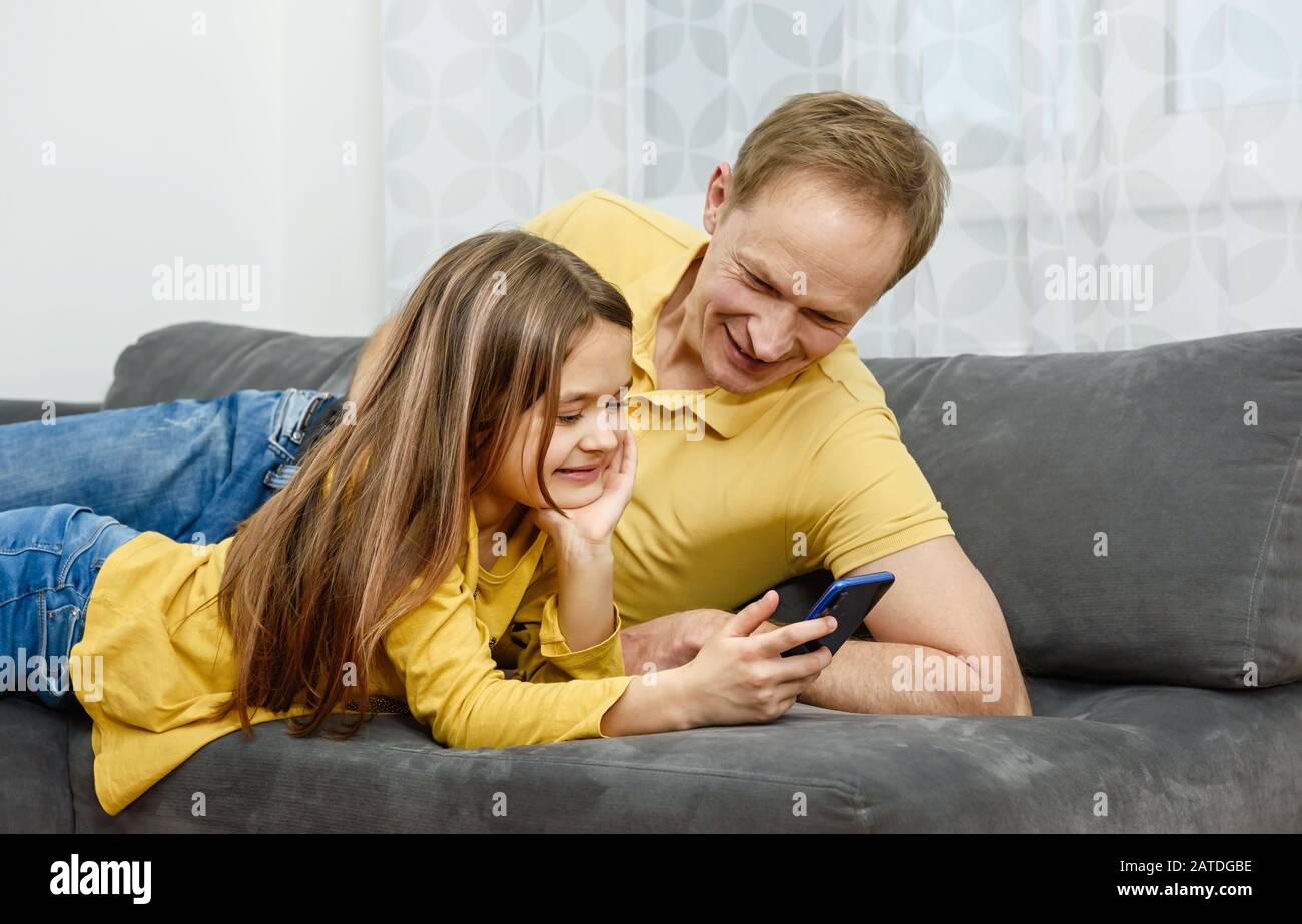 Père et fille regardant dans le smartphone et passer un excellent séjour. Un concept de famille heureux. Banque D'Images