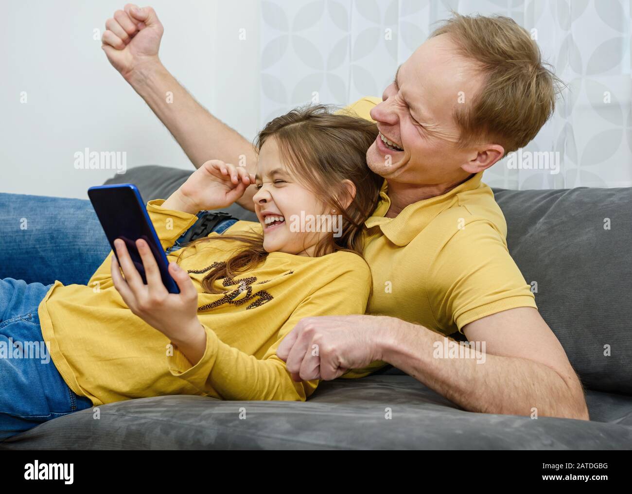 Père et doughter regarder dans le smartphone et avoir un excellent temps. Un concept de famille heureux. Banque D'Images