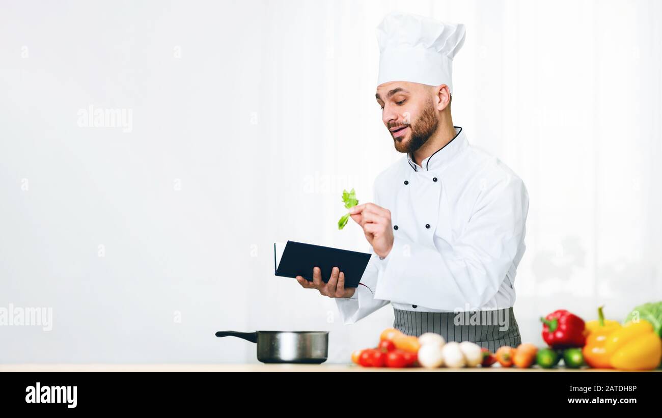 Homme Apprendre À Cuisiner Lecture Livre De Recettes Dans La Cuisine, Panorama Banque D'Images