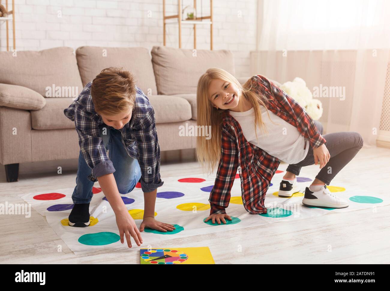 Garçon Et Fille Jouant À Twister Game Together Sur Plancher Intérieur Banque D'Images