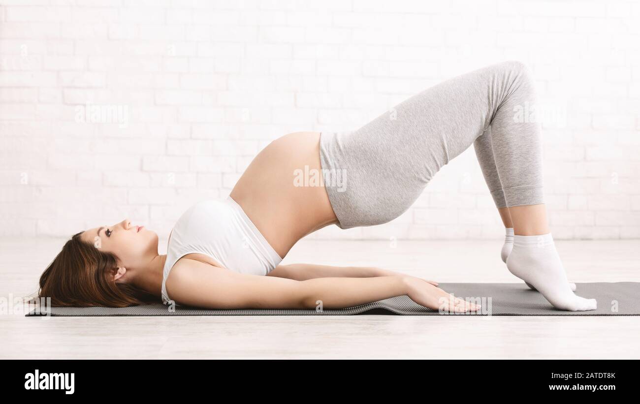 Femme enceinte s'étirant sur tapis de yoga, panorama Banque D'Images