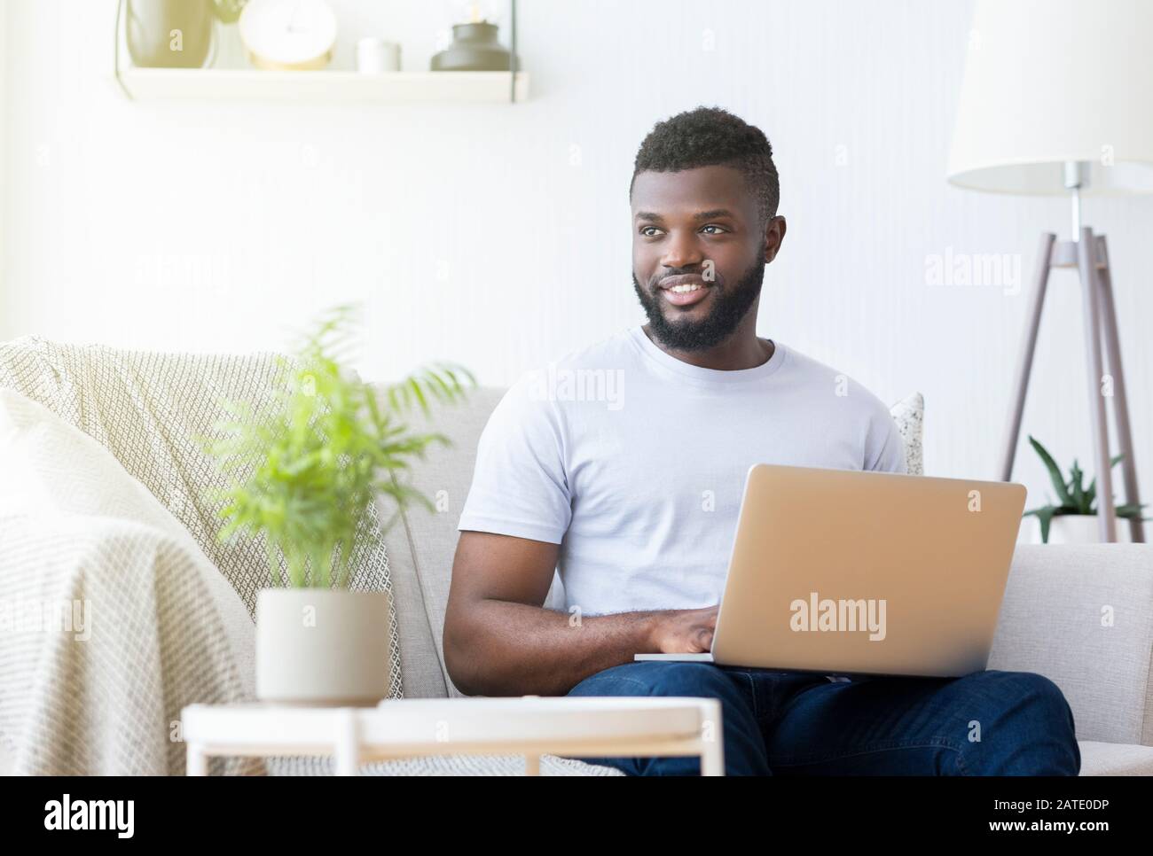 Homme noir positif tapant sur ordinateur portable à la maison Banque D'Images