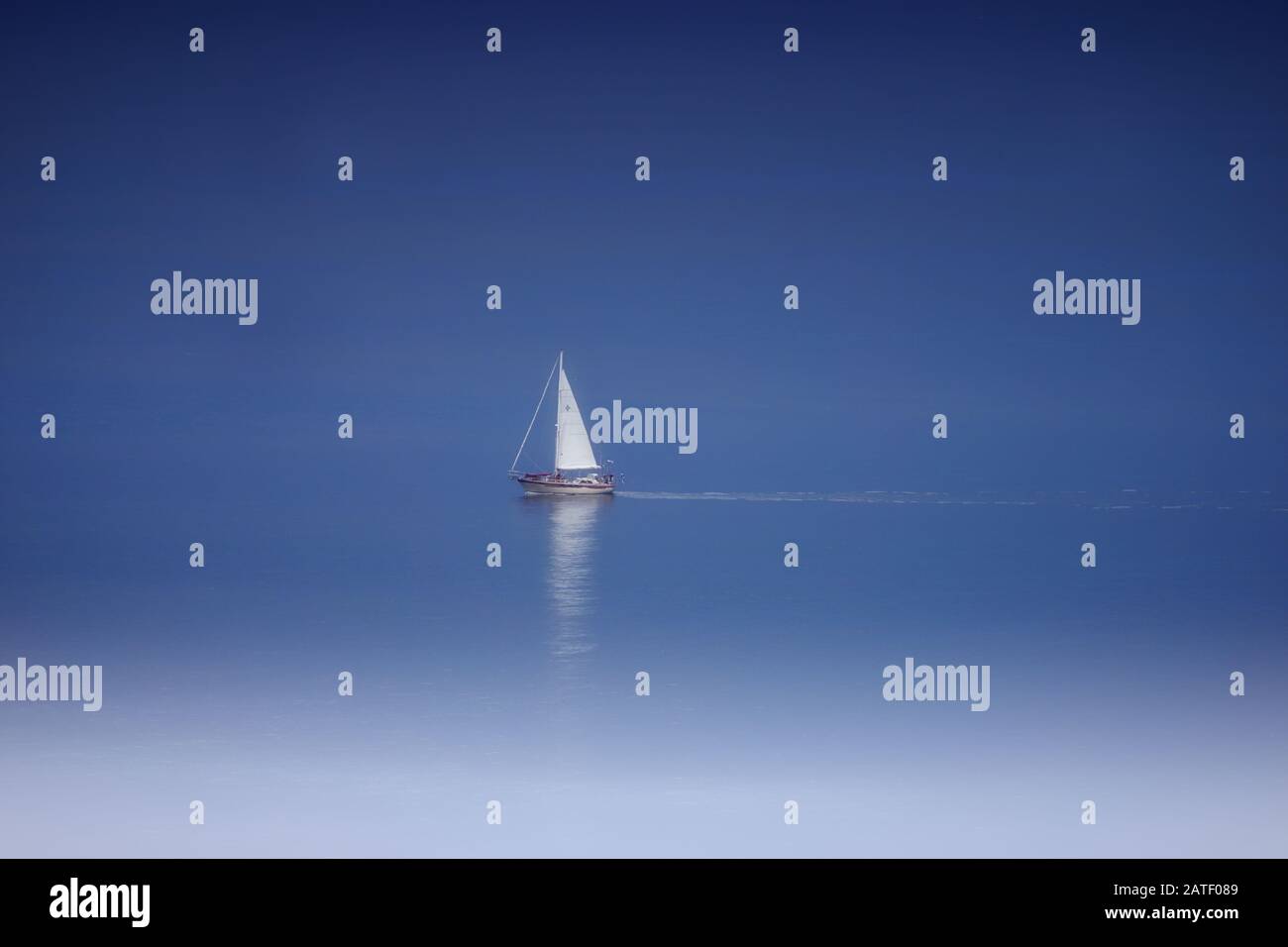 Voilier blanc solitaire au milieu d'une mer bleue calme Banque D'Images