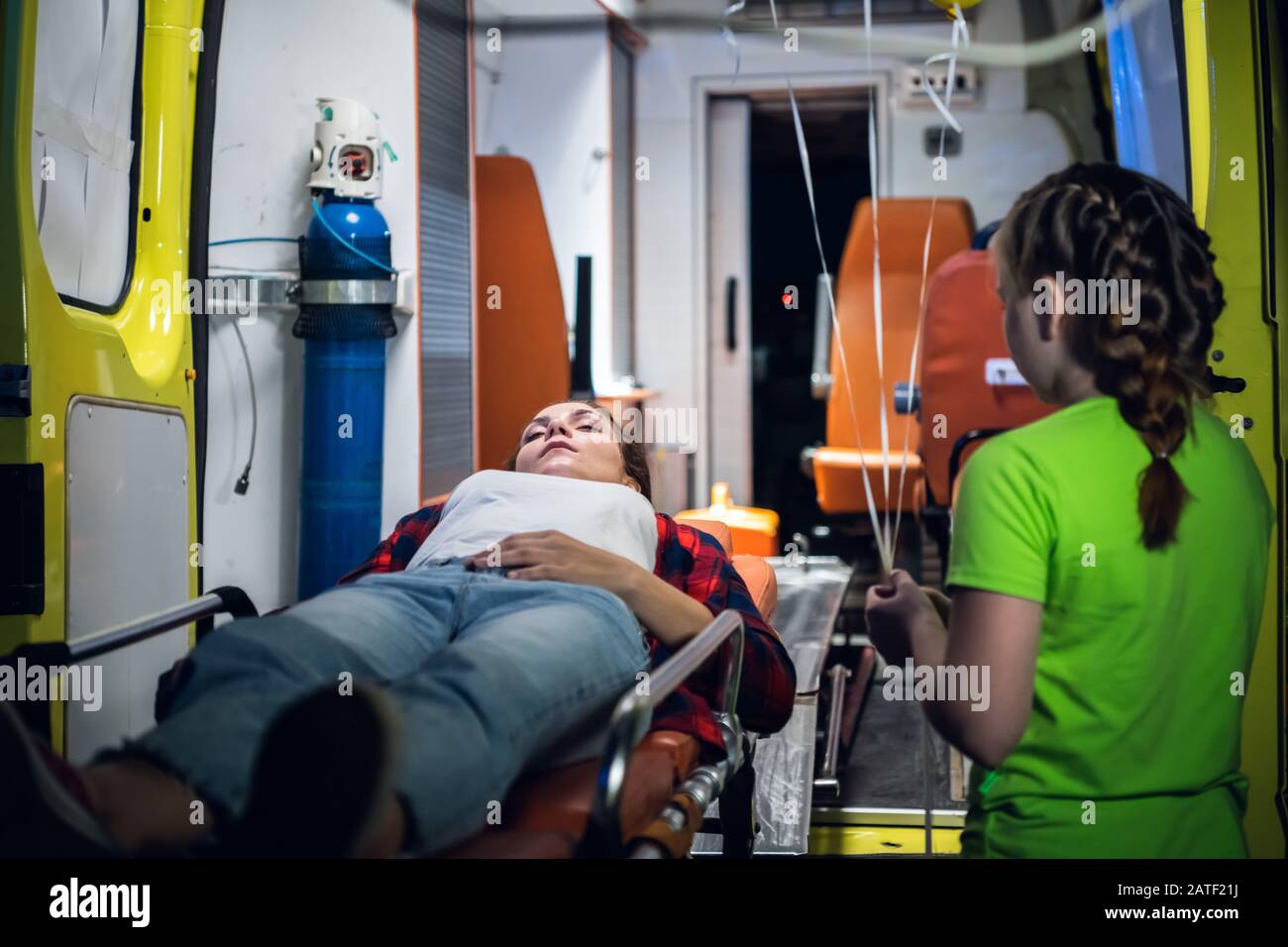 Petite fille se tient à côté d'une femme posée sur une civière dans la  voiture d'ambulance Photo Stock - Alamy