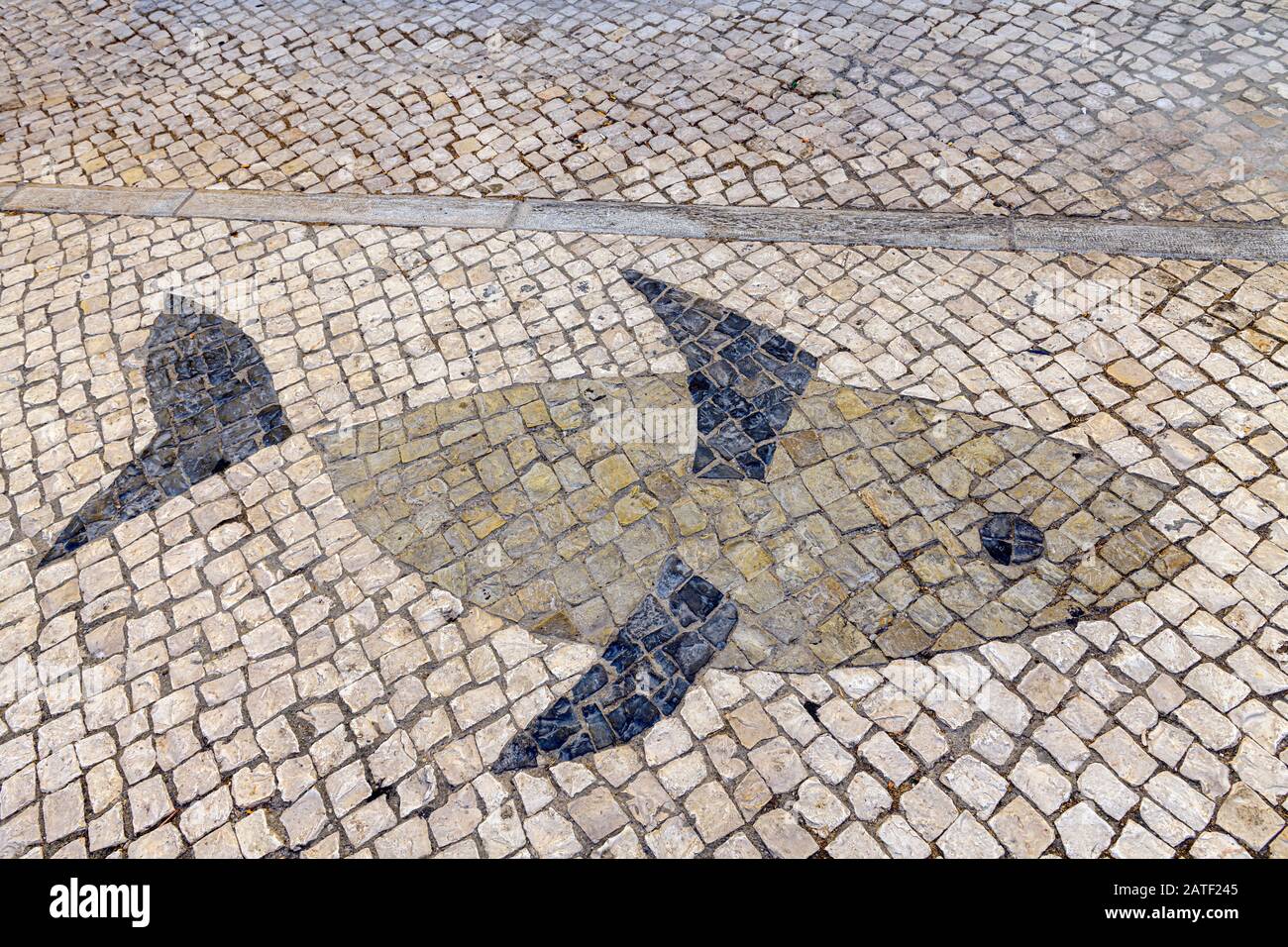 Motif de poisson en pierres de galets calcada traditionnelles portugaises. Fuseta, Algarve, Portugal. Banque D'Images