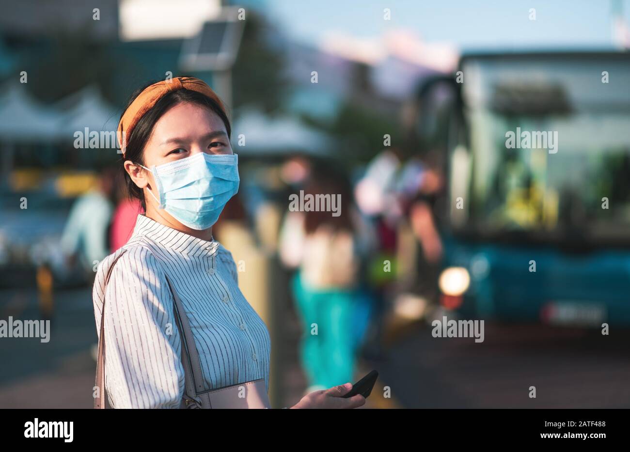 Fille asiatique portant un masque pour empêcher le virus à la gare routière Banque D'Images