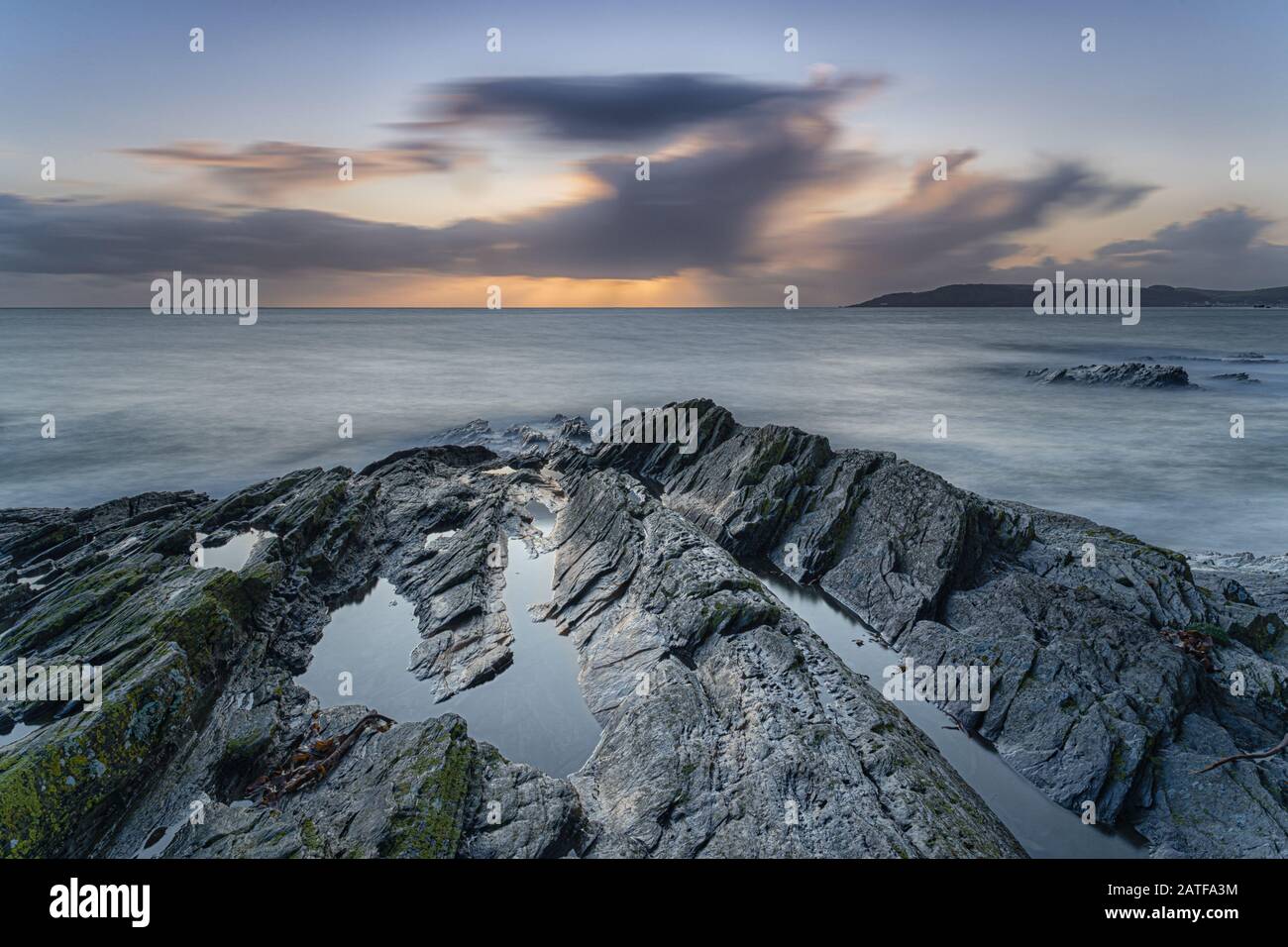 Milky mer au coucher du soleil sur les rochers à Bovisand dans Devon Banque D'Images