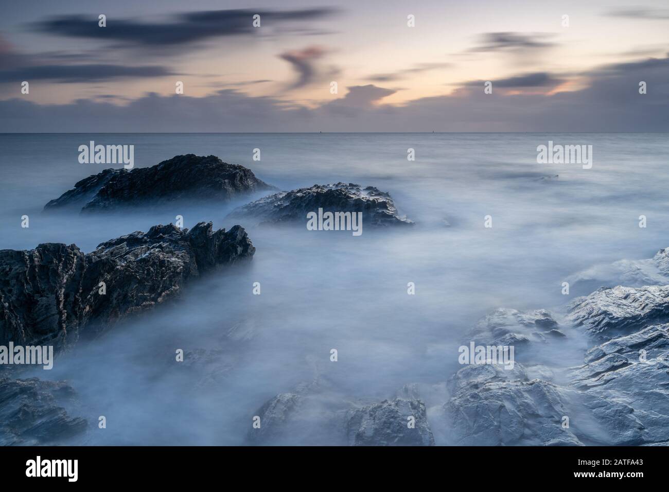 Milky mer au coucher du soleil sur les rochers à Bovisand dans Devon Banque D'Images