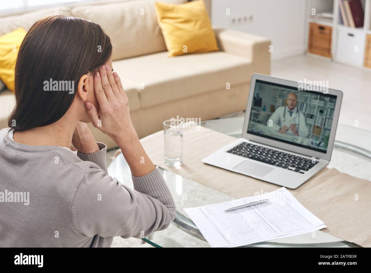Jeune femme malade avec ses mains sur les temples ayant une consultation médicale en ligne Banque D'Images