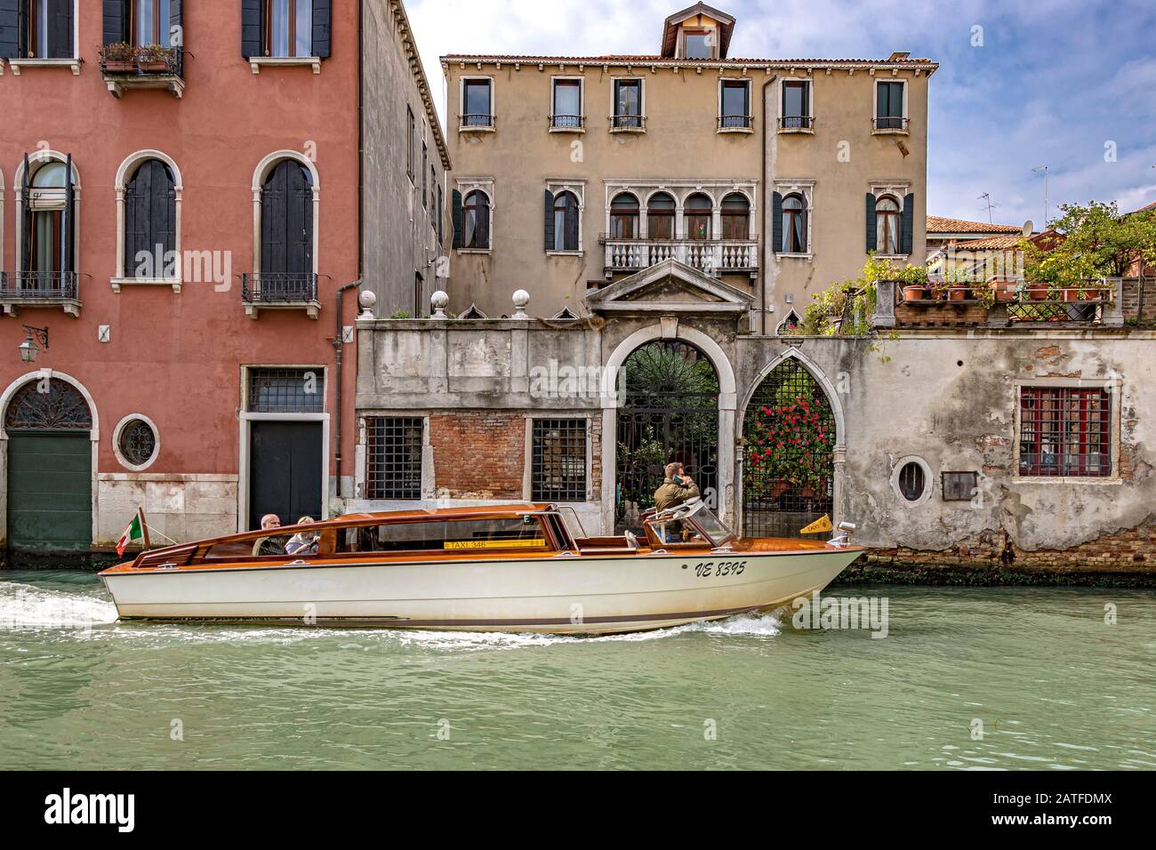 Un bateau-taxi de Venise parle sur son téléphone mobile qui navigue sur son chemin le long du canal Rio Dei Medicanti a dans le quartier Cannaregio de Venise, Italie Banque D'Images
