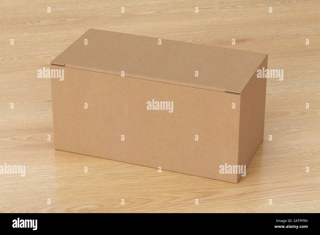 Boîte large en carton vierge avec couvercle rabattable fermé sur fond en bois. Chemin de détourage autour de la maquette de boîte Banque D'Images