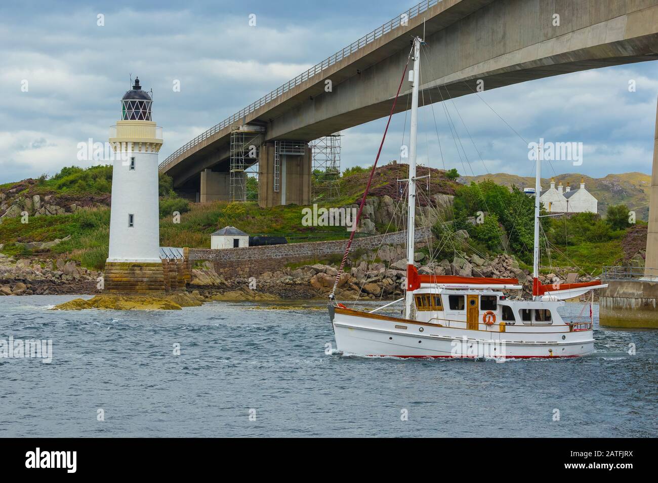 Phare de Kyleakin à gauche du pont de l'île de Skye avec bateau de croisière blanc et rouge passant par le pont. Horizontal. Espace de copie Banque D'Images