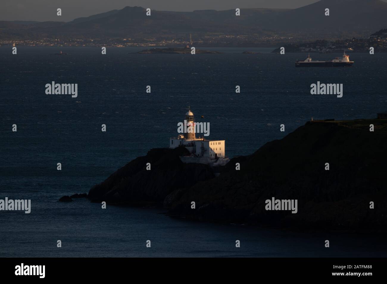 Le phare BDaily, Howth. co. Dublin, phare BDaily sur les falaises de Howth, vue du phare BDaily depuis la falaise où le cargo est en arrière-plan Banque D'Images