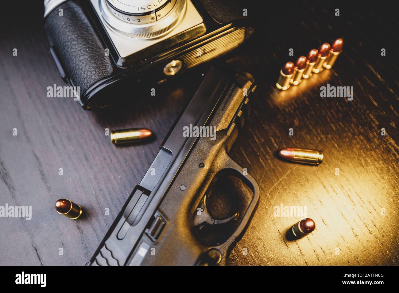 Pistolet, appareil photo et balles sur table en bois Banque D'Images