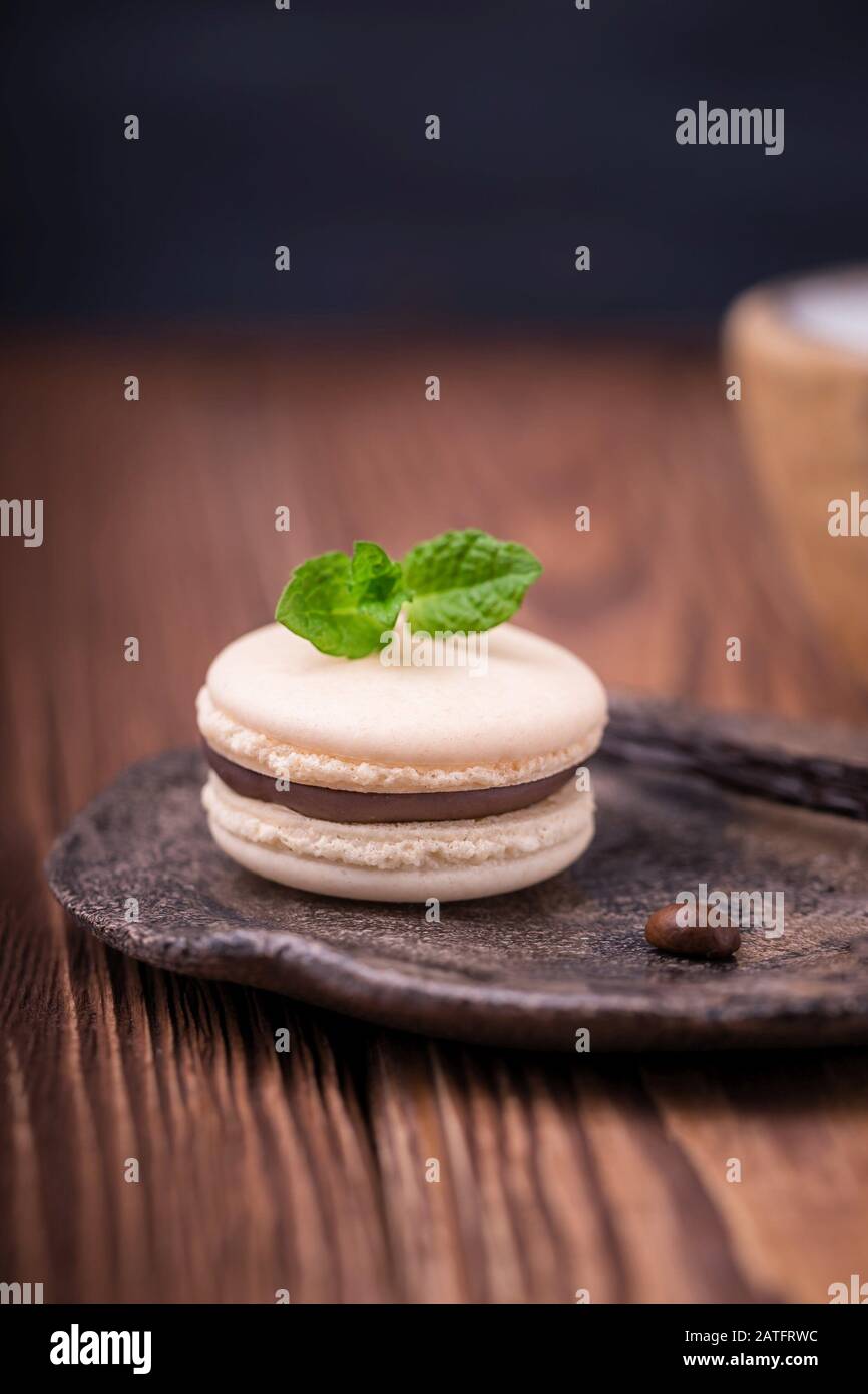Macaron ou macaron de chocolat à la vanille fait maison avec feuille de menthe sur fond en bois Banque D'Images