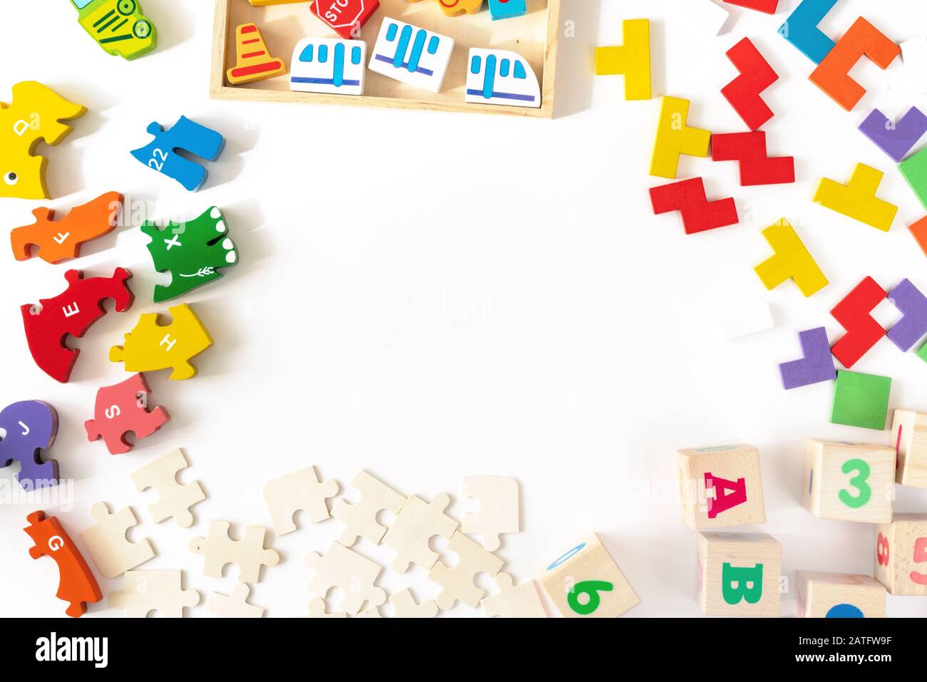 Jouets colorés pour enfants sur fond blanc. Cadre de développement de blocs colorés, voitures et avion, puzzles. Vue de dessus. Pose plate. Espace de copie pour le texte Banque D'Images