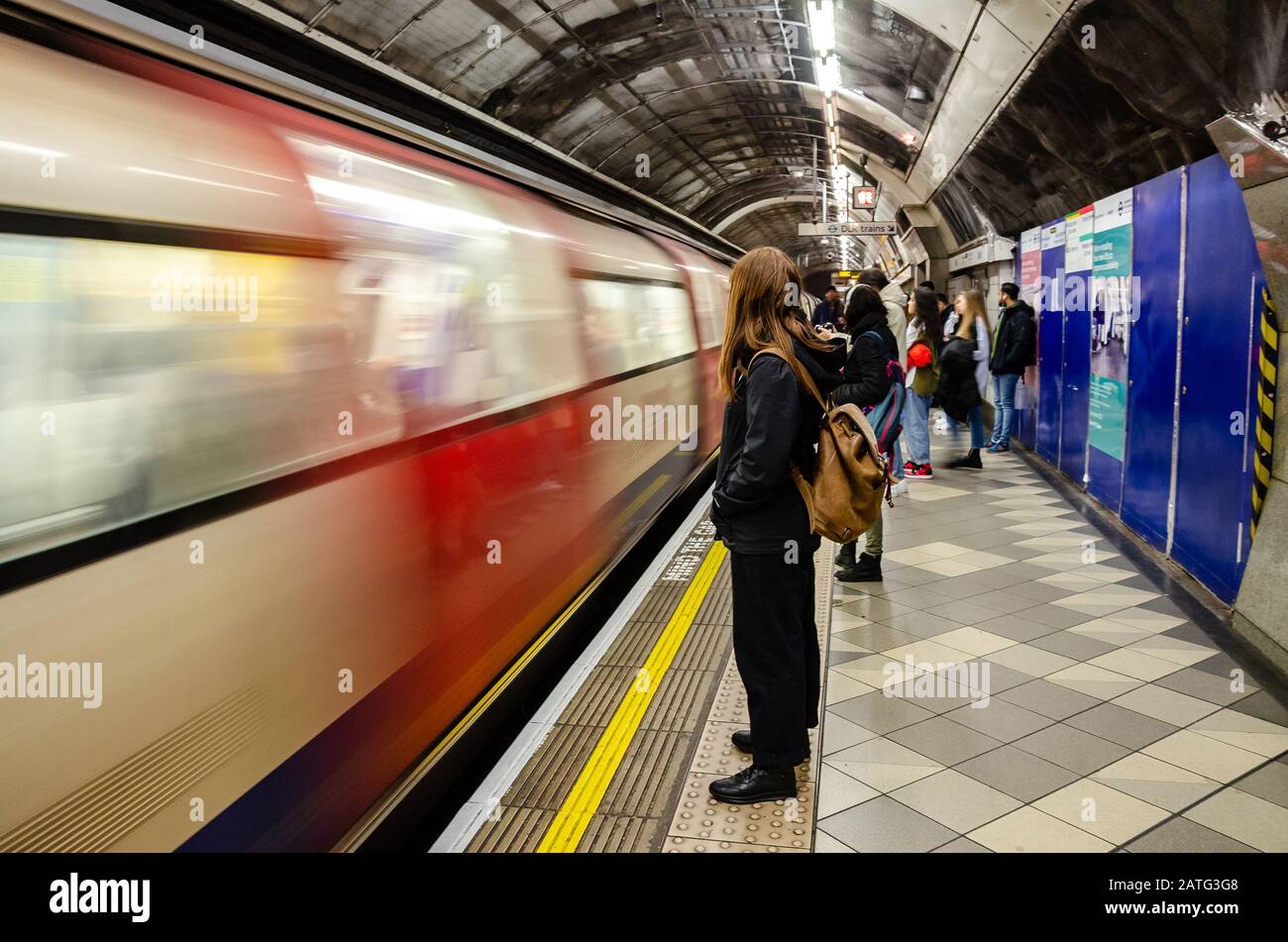 Les passagers se tiennent debout et attendent sur la plate-forme lorsqu'un train souterrain de Londres arrive sur la plate-forme de la gare Bank Banque D'Images