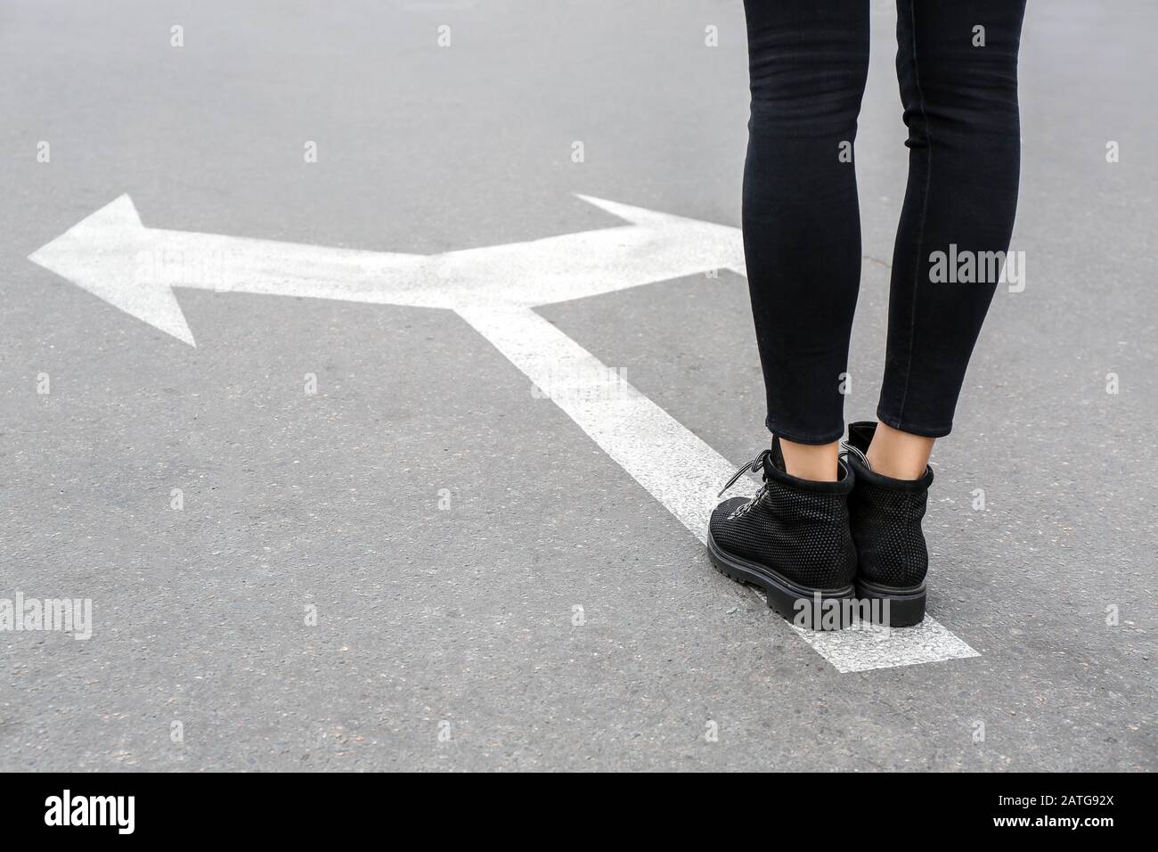 Jeune femme debout sur la route avec des flèches de marquage. Concept de choix Banque D'Images