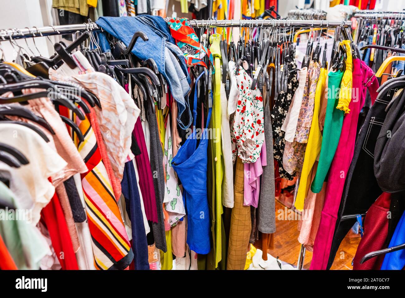 Section de dégagement bondée dans un magasin de vêtements, avec divers vêtements colorés placés étroitement sur des racks dans un ordre particulier; concept de mode rapide Banque D'Images
